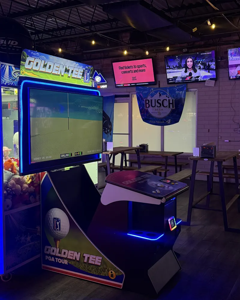 Golden Tee PGA Tour golf cabinet with TVs and high-top tables behind it